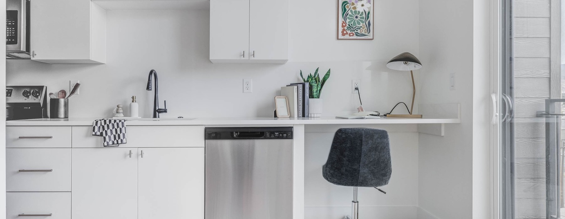 a kitchen with white cabinets, a desk and a chair