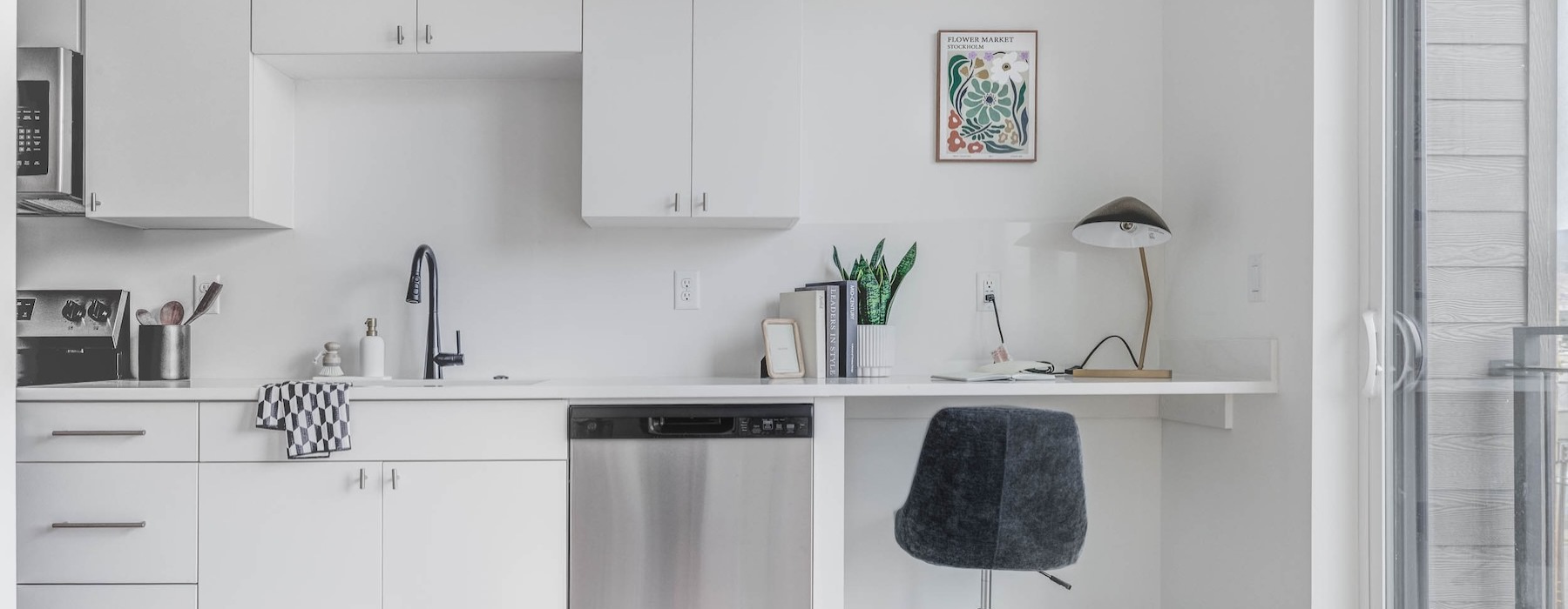 a kitchen with white cabinets, a desk and a chair